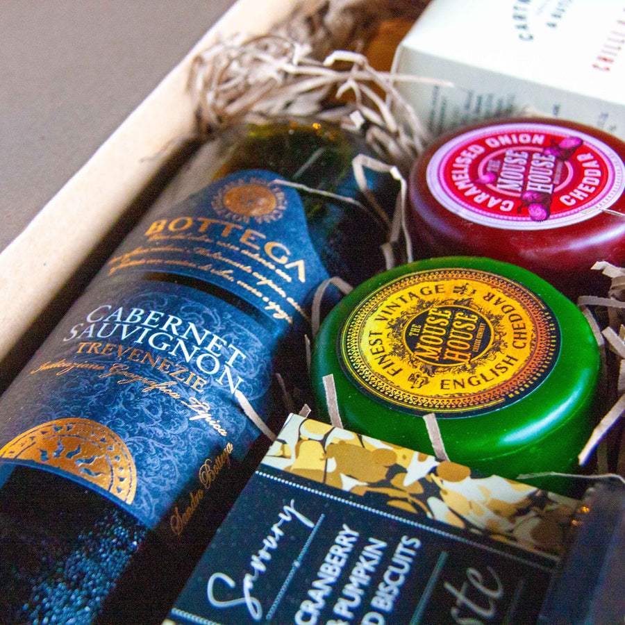 The Wine & Cheese hamper opened out on a table top. A bottle of Cabernet Sauvignon laid next to cheeses from The Mouse House.